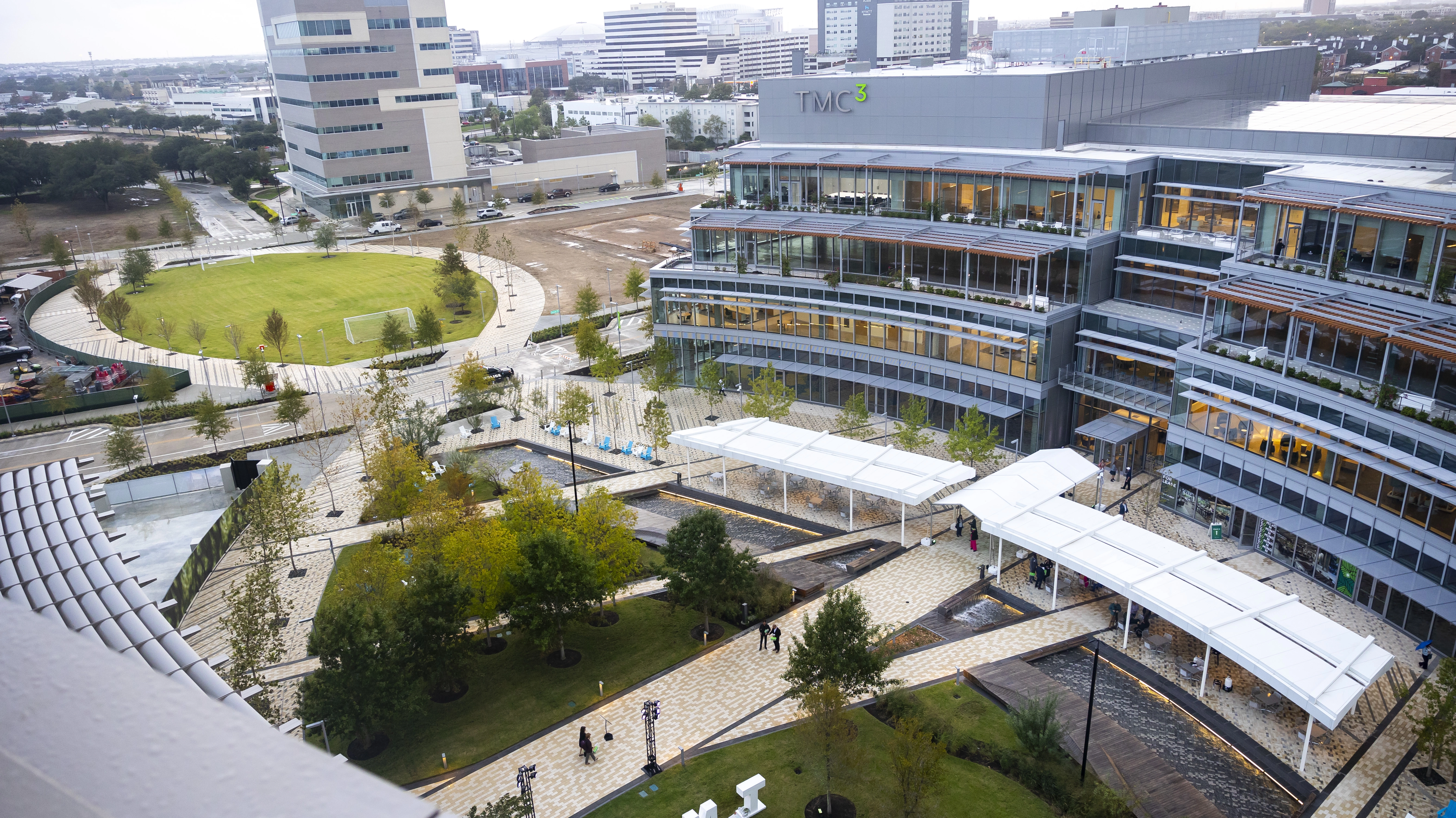 Exterior view of the TMC3 Collaborative Building in Helix Park with the Texas Medical Center of Houston skyline behind it