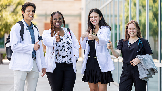 Group of people standing outside building doing thumbs up