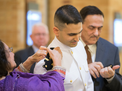 A medical student receiving his military commission. His parents putting his epaulets on his uniform